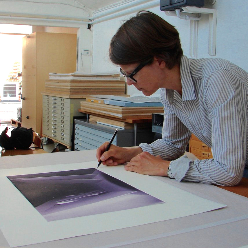 Artist Anette Harboe Flensburg signing a purple colour photogravure print on a work table at the Printer's Proof intaglio print studio.