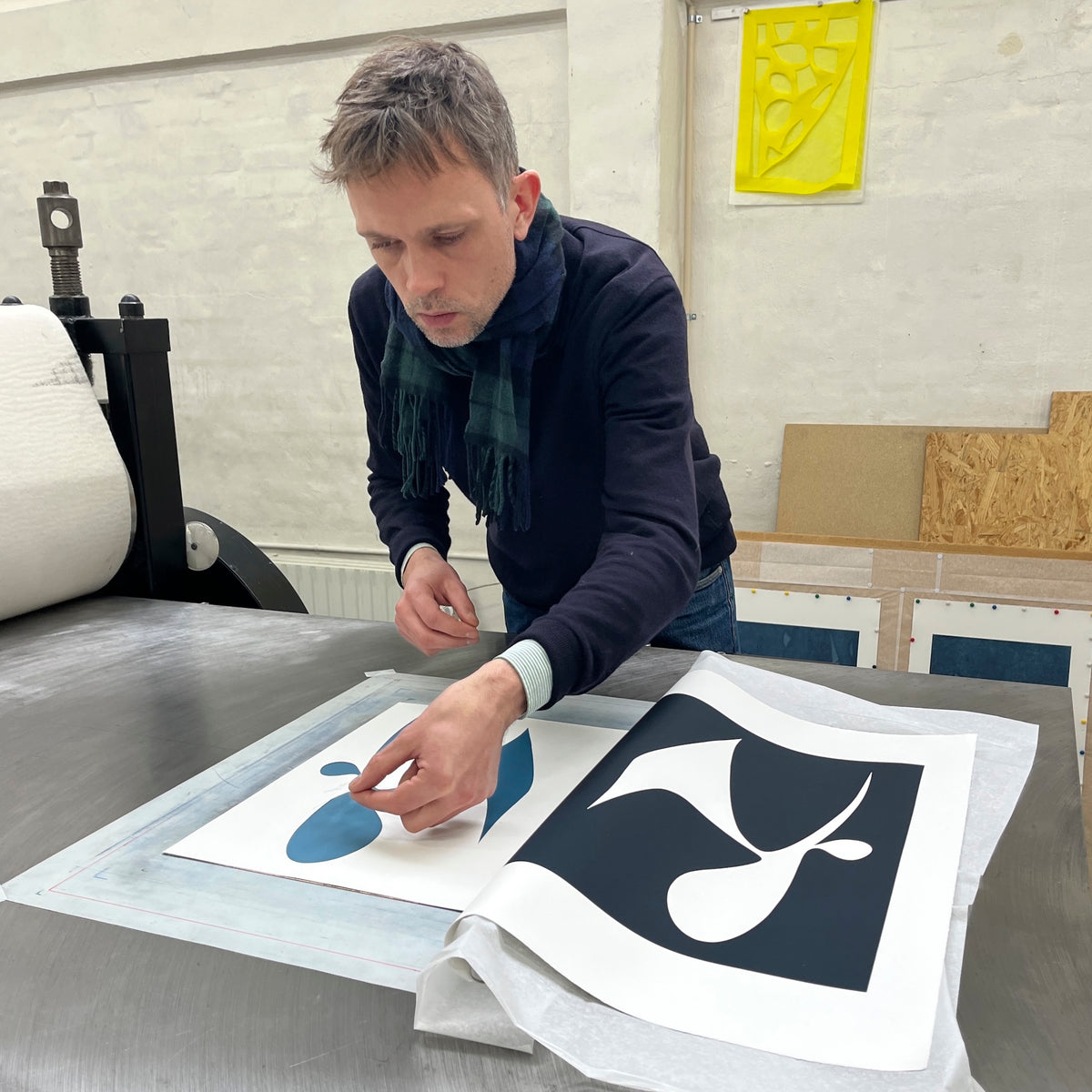 Artist Mathias Malling Mortensen arranging a paper cutout stencil on a printing press at Printer's Proof printmaking studio to make a unique work on paper.