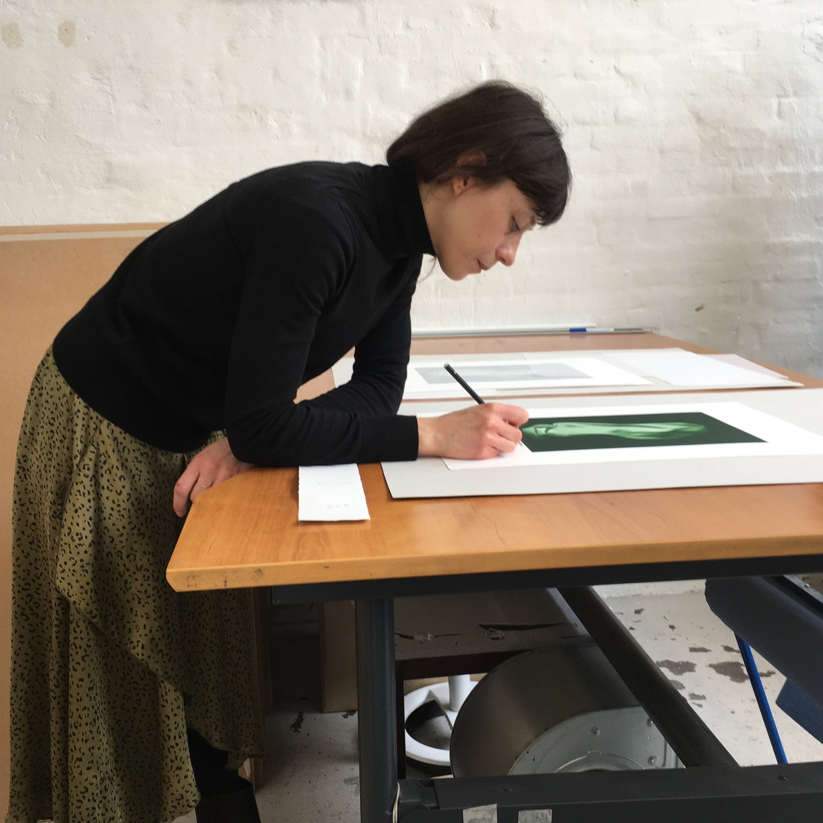 Artist Valérie Collart at a Printer's Proof printmaking studio, signing a limited-edition photogravure print.